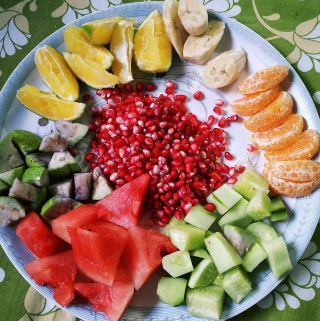 Colorful fruit plate with pomegranate, watermelon, orange, and cucumber